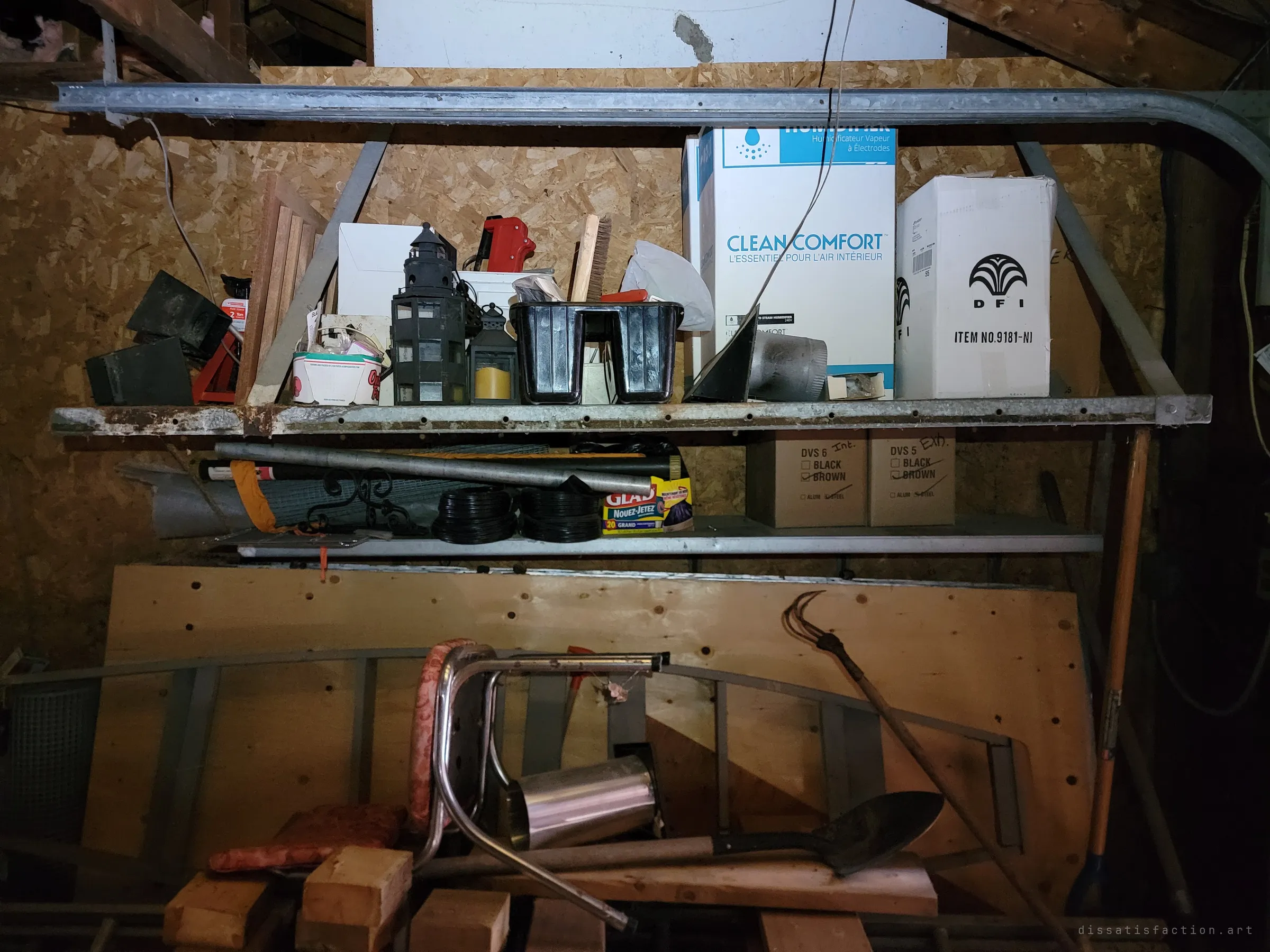 Metal shelving along the garage wall stacked with boxed humidifier parts, lanterns and tools, with a chrome chair and shovel below. Everything sits where it was last put away.