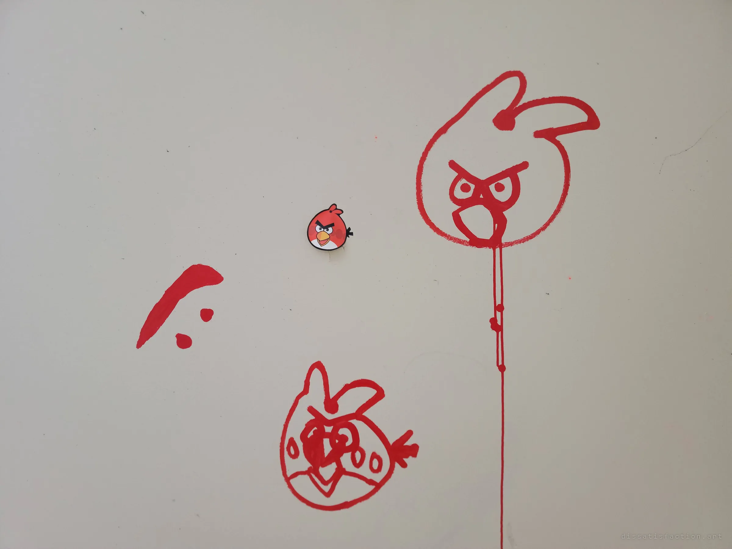 Close-up of red paint doodles of angry birds on a pale wall around a small printed sticker of the same cartoon bird, one drawing dripping a long line of paint down the wall. The detail that gives the album its nickname.