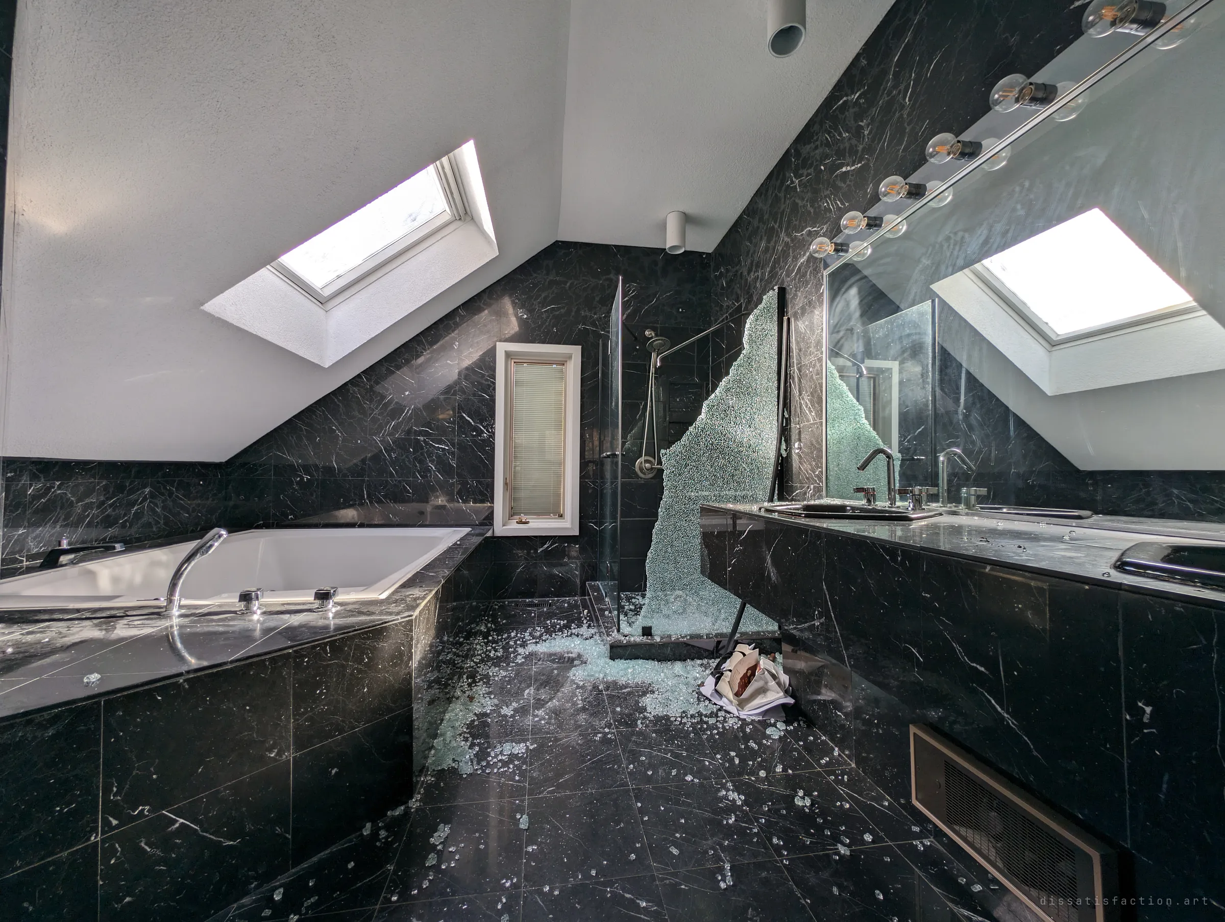 A black marble ensuite under a sloped skylight ceiling, its glass shower screen shattered across the floor in a spray of fragments. The one violent scene in an otherwise untouched house.