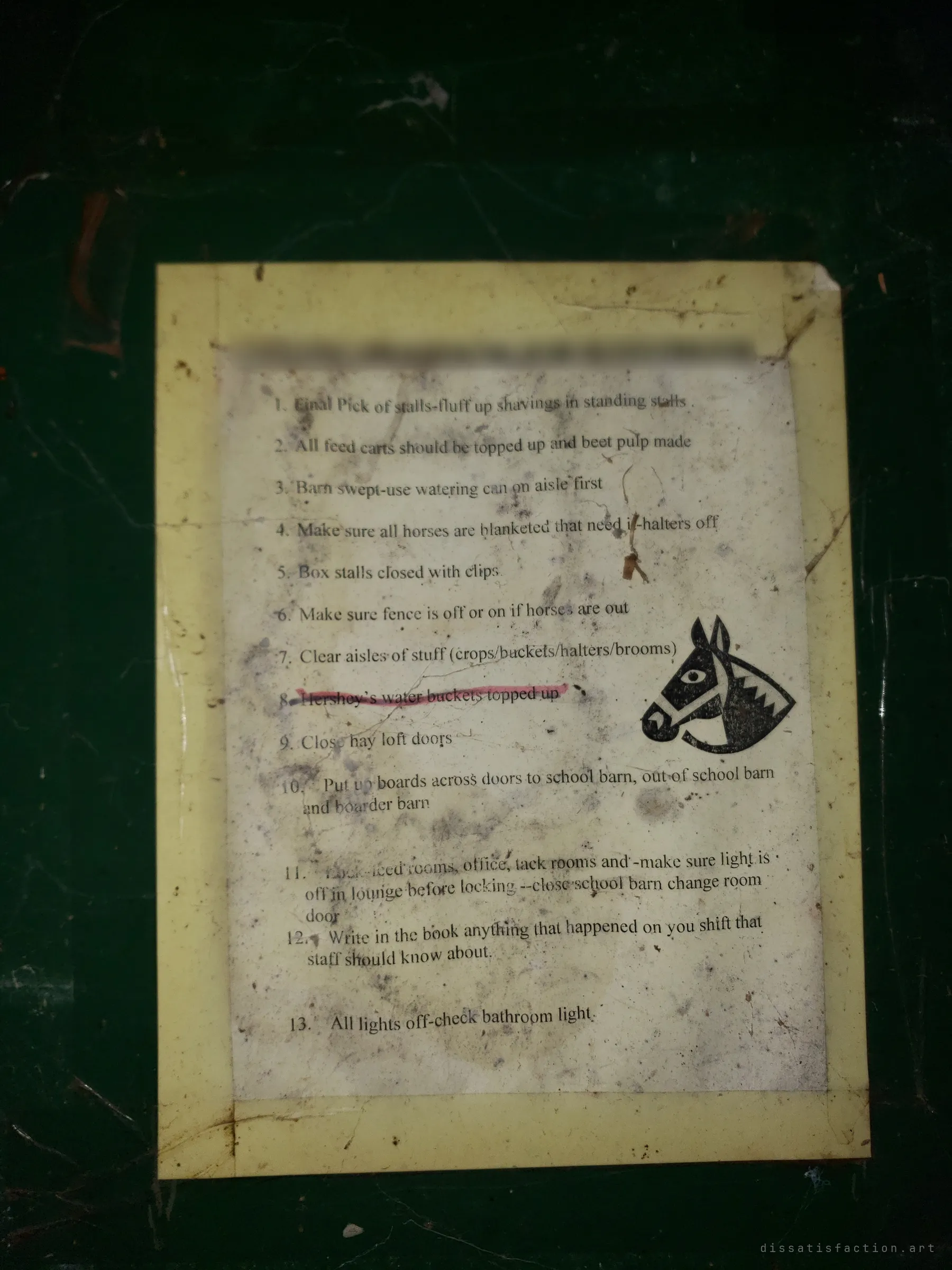 A dirty printed checklist of end-of-day closing chores, with a horse-head clip-art, taped to a dark green wall. One line about a particular horse's water buckets has been struck out in pink.