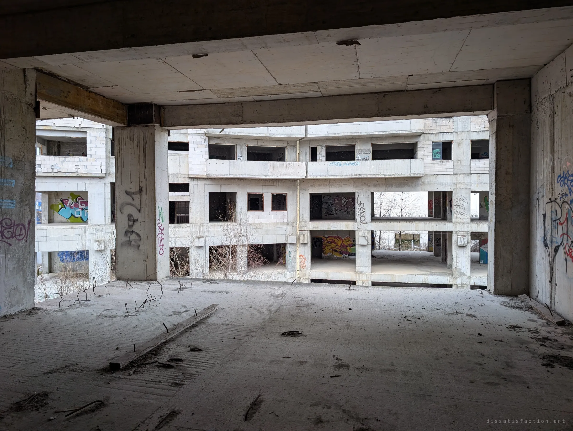 From an upper floor, the view across to a second unfinished wing: tiers of empty window openings and graffiti pieces on every level.