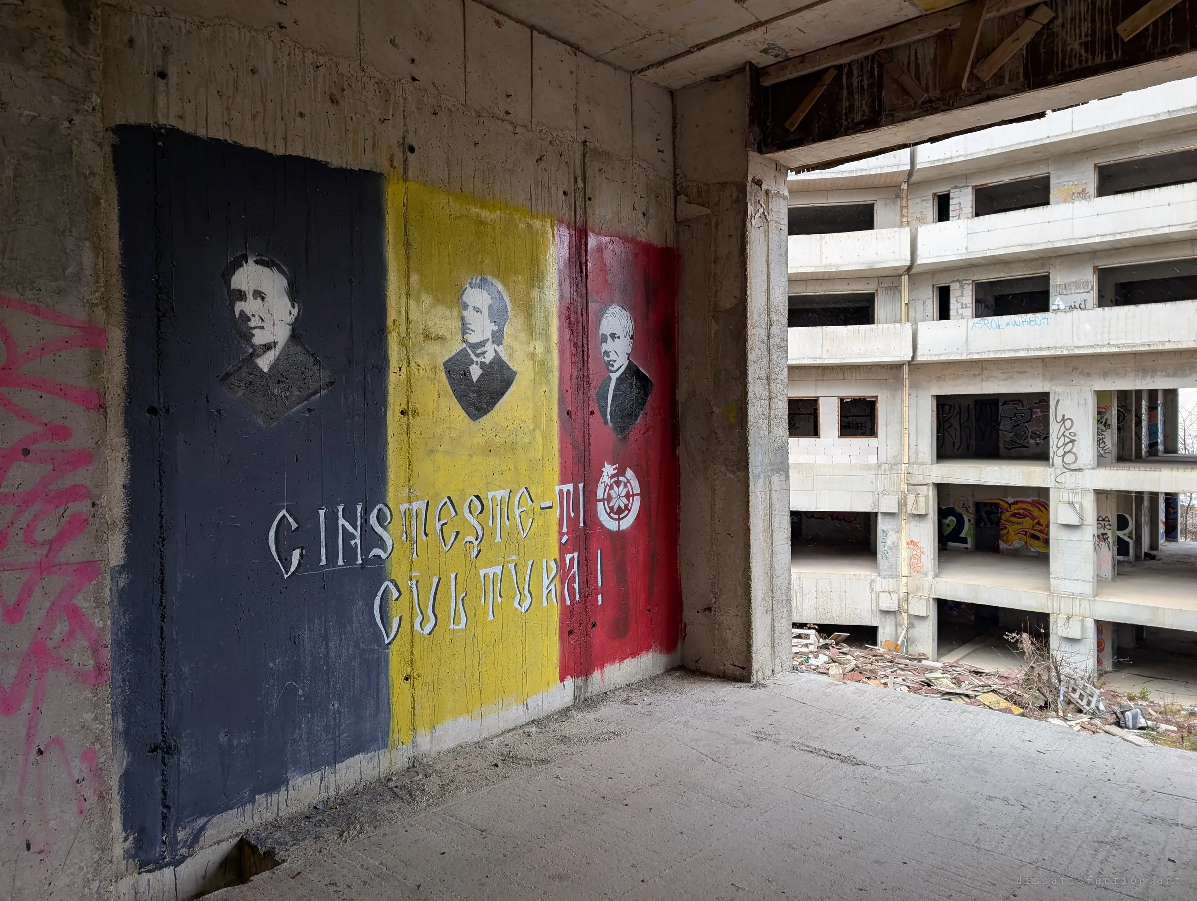 A painted tricolour mural with stencilled portraits of three historical figures and a slogan about honouring culture, beside an opening onto the opposite wing.