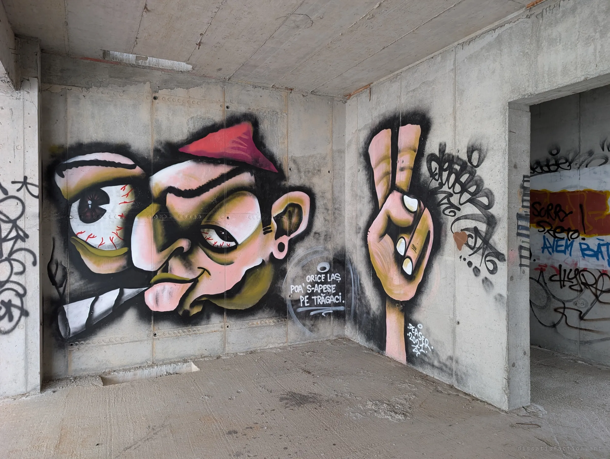 A large cartoon mural of a bug-eyed smoking face beside a hand making a peace sign, signed and dated by the artist. One of the more finished pieces in the building.