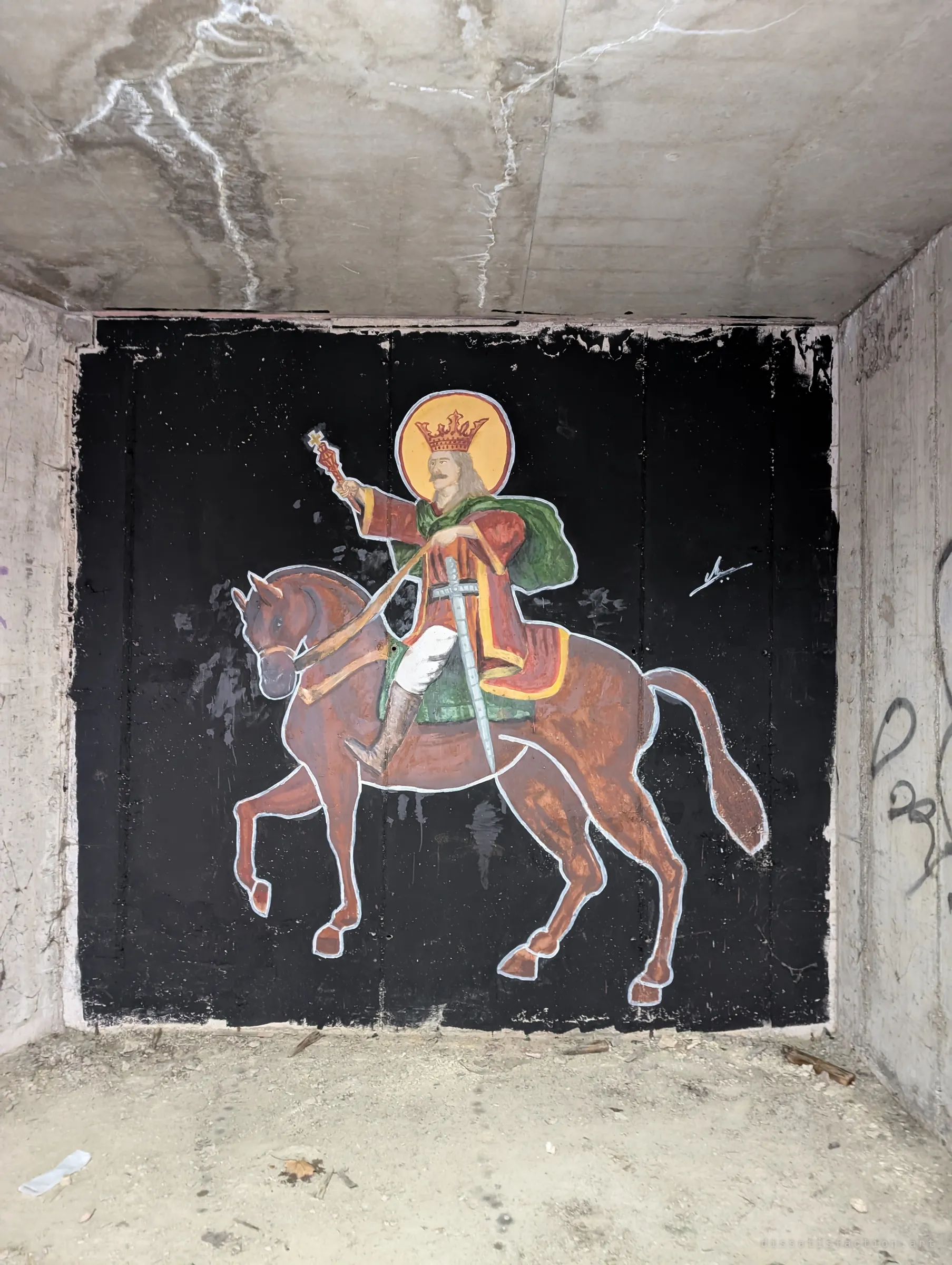 A crowned, haloed rider on a chestnut horse is painted in icon style on a black panel inside a concrete bay. Devotional art set in a bare shell.