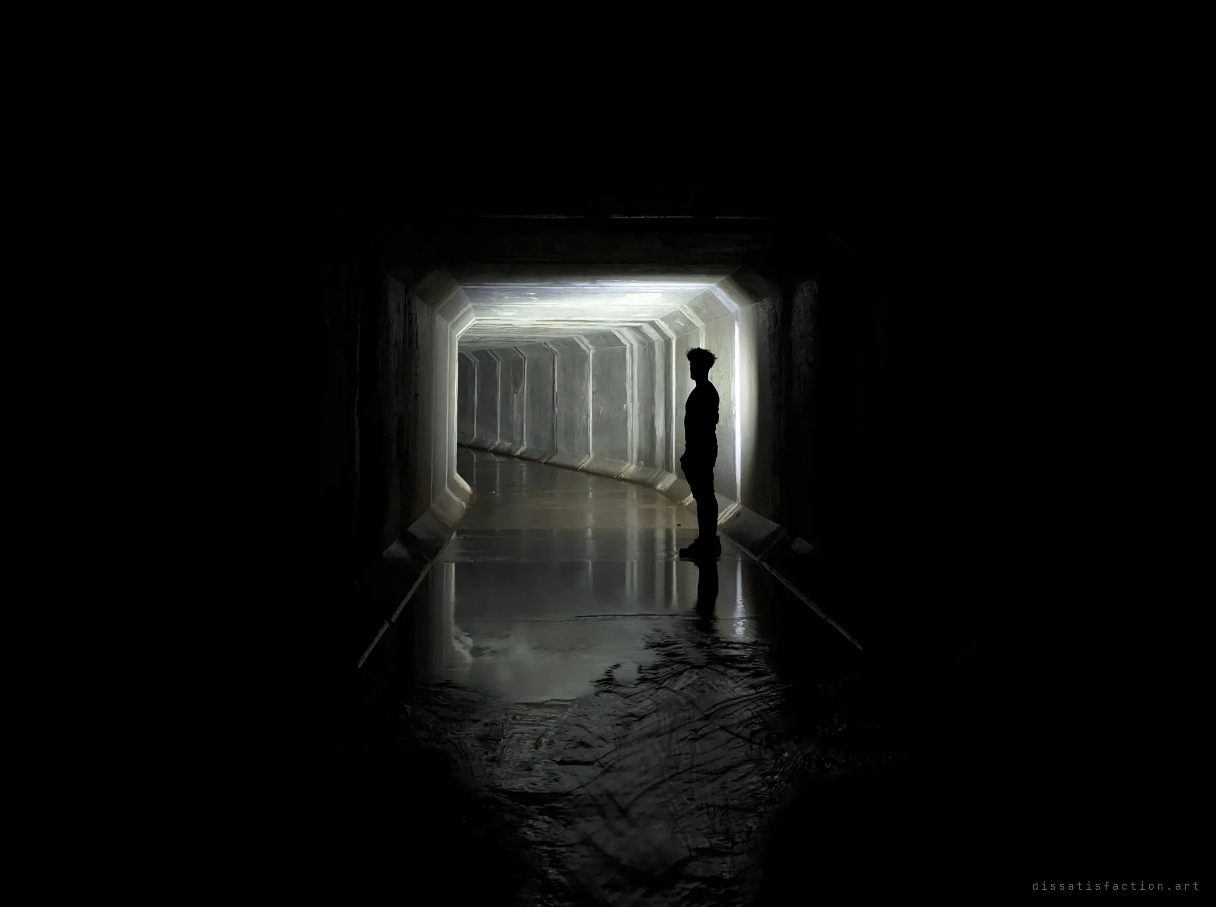A silhouetted figure in profile stands at the edge of a lit bend in the box drain, the rest of the tunnel falling to black. The scale of the person shows the drain's height.