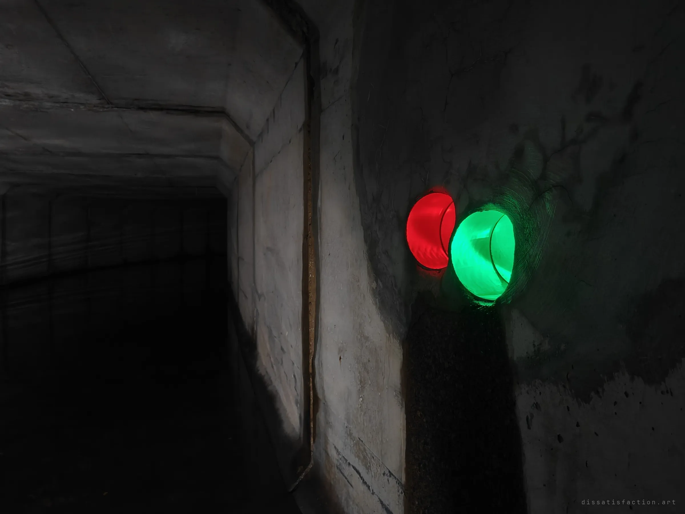 Two small side pipes in the drain wall, glowing red and green from lights placed inside them, beside a dark concrete tunnel leading away. Light painting turns a plain culvert wall into something like a signal.