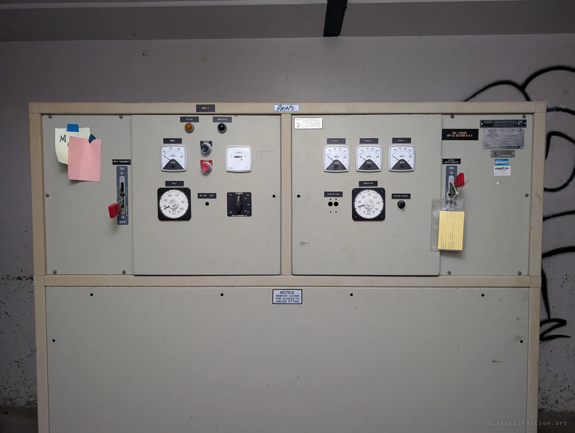 Close-up of a motor-generator control panel with ammeters, a voltmeter, start and stop buttons and a red-handled disconnect, still tagged with notes and a lockout card.