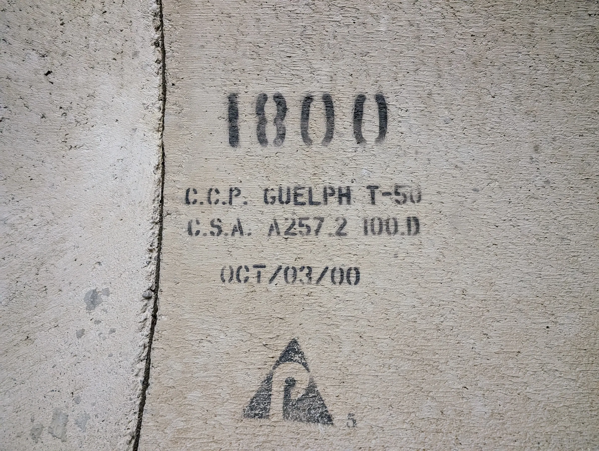 A crisper stencil on the pipe wall with a smaller diameter, a 2000 casting date and a maker's triangle logo, showing the tunnel narrowing as it goes on.
