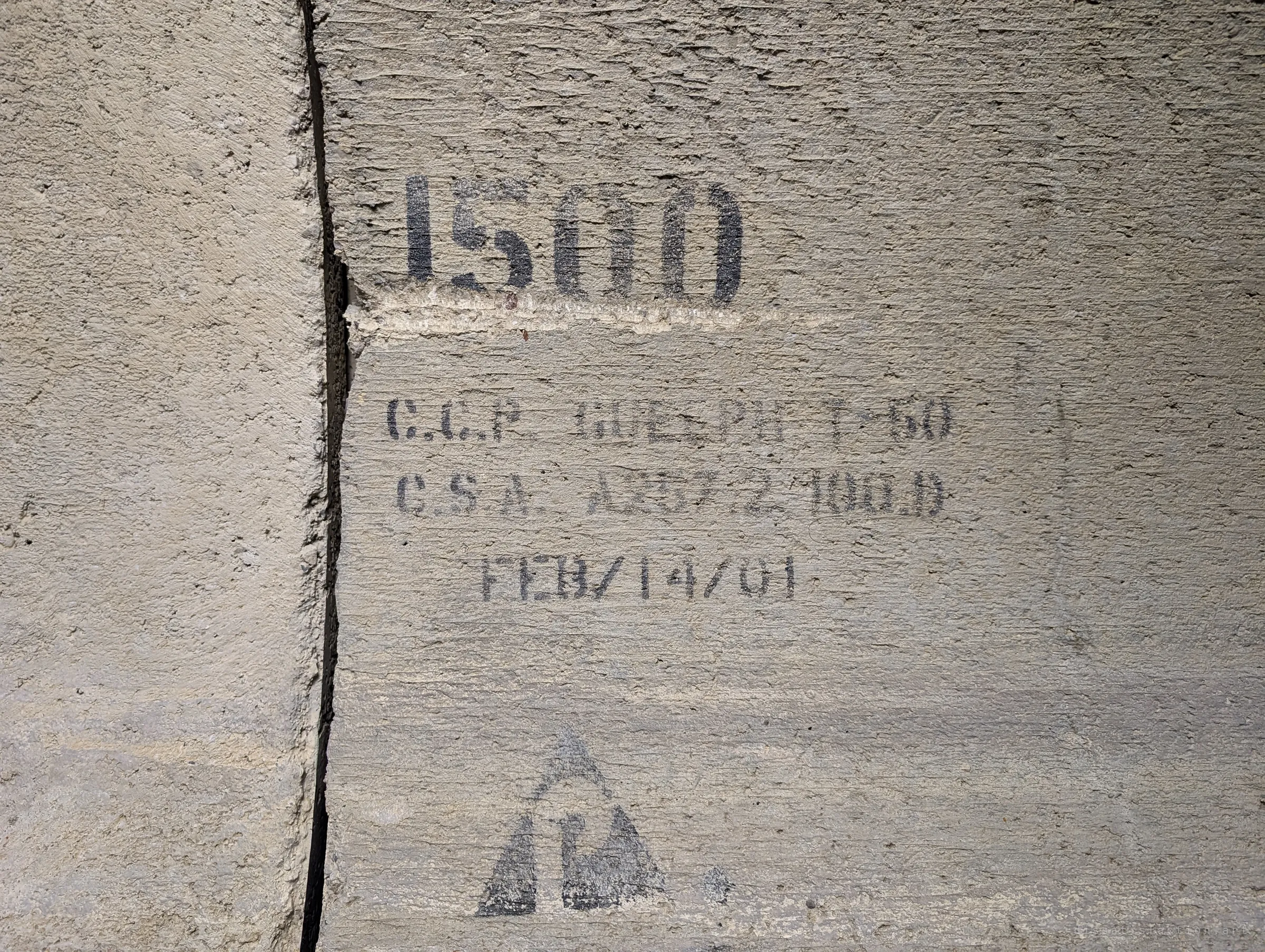 A faded stencil showing the smallest size in the series and a 2001 casting date, beside a cracked joint. It is the last step in the pipe shrinking section by section.