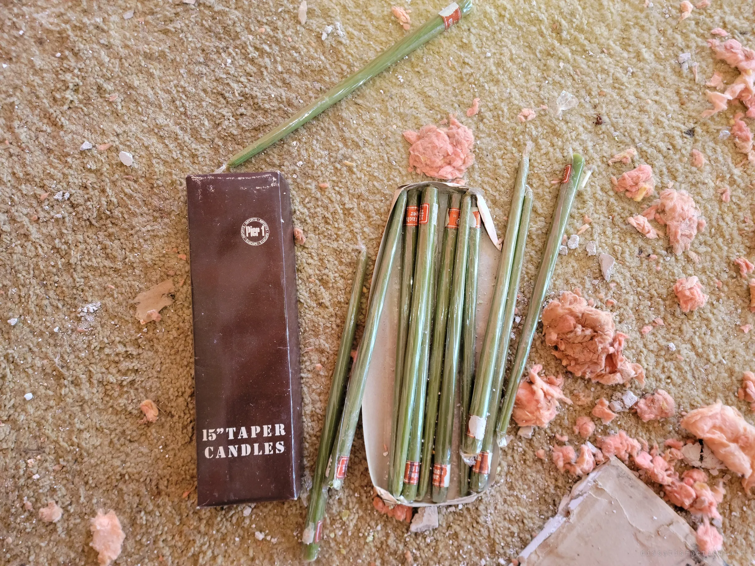 A box of long green taper candles spilled across a shag carpet among clumps of pink insulation and plaster crumbs. Unused, still in their wrappers.