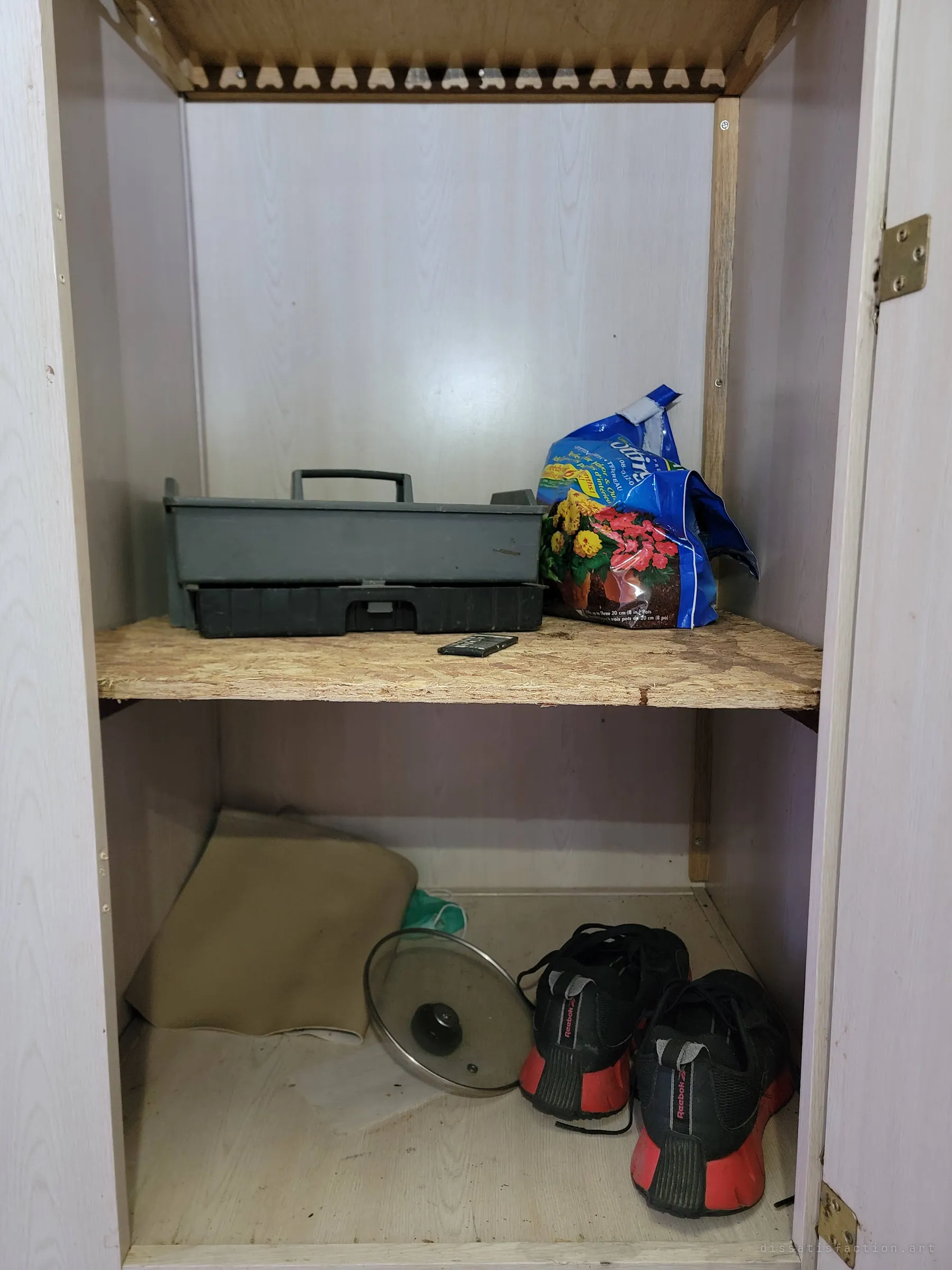 An open closet holds a plastic tool caddy, a bag of potting soil and a pair of worn sneakers. Small traces of the last person who stayed here.