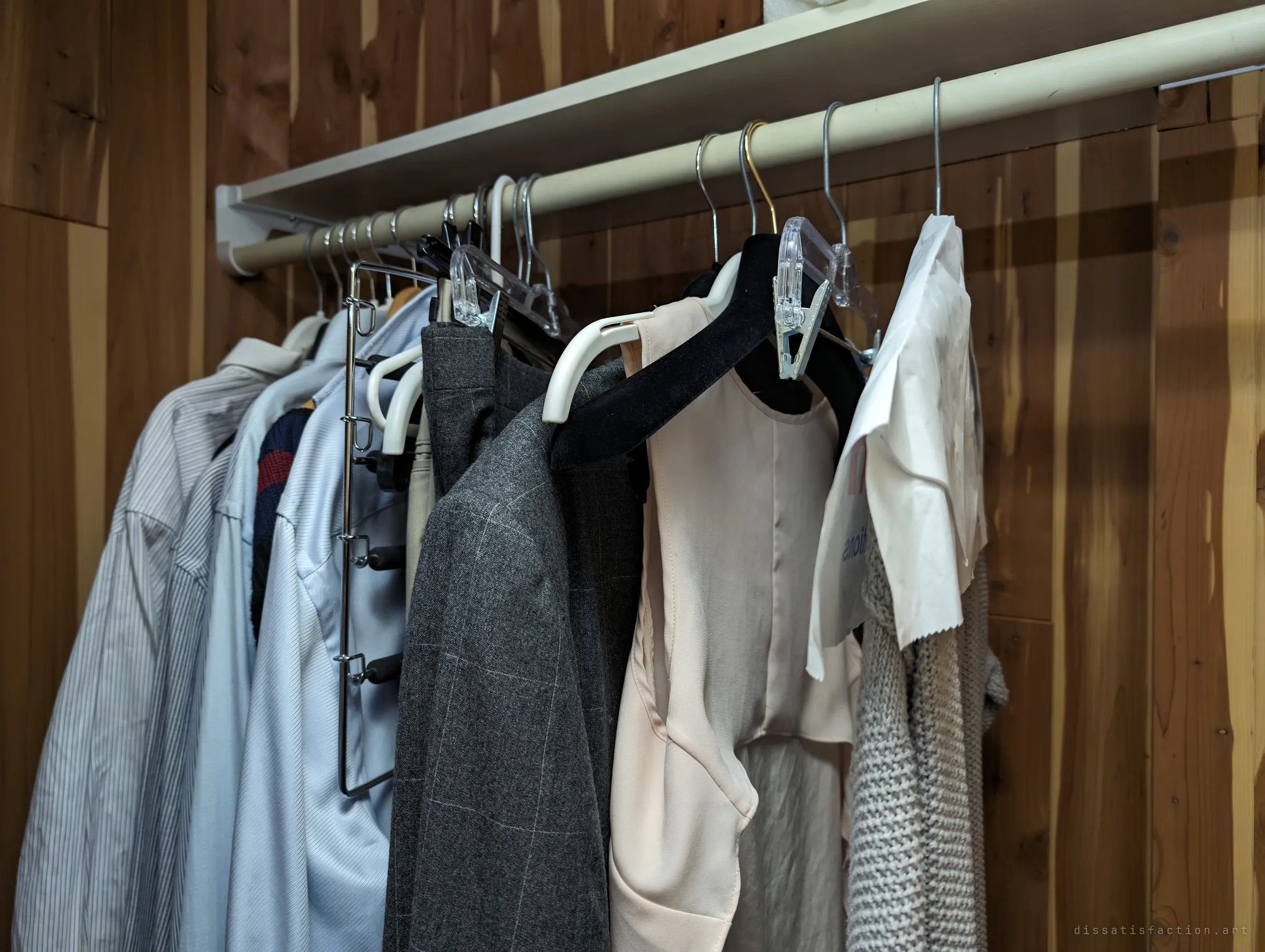 Shirts, a grey blazer and a blouse still hanging in a cedar-lined closet, one with its dry-cleaning paper on. The wardrobe was left as if someone would be back to dress.