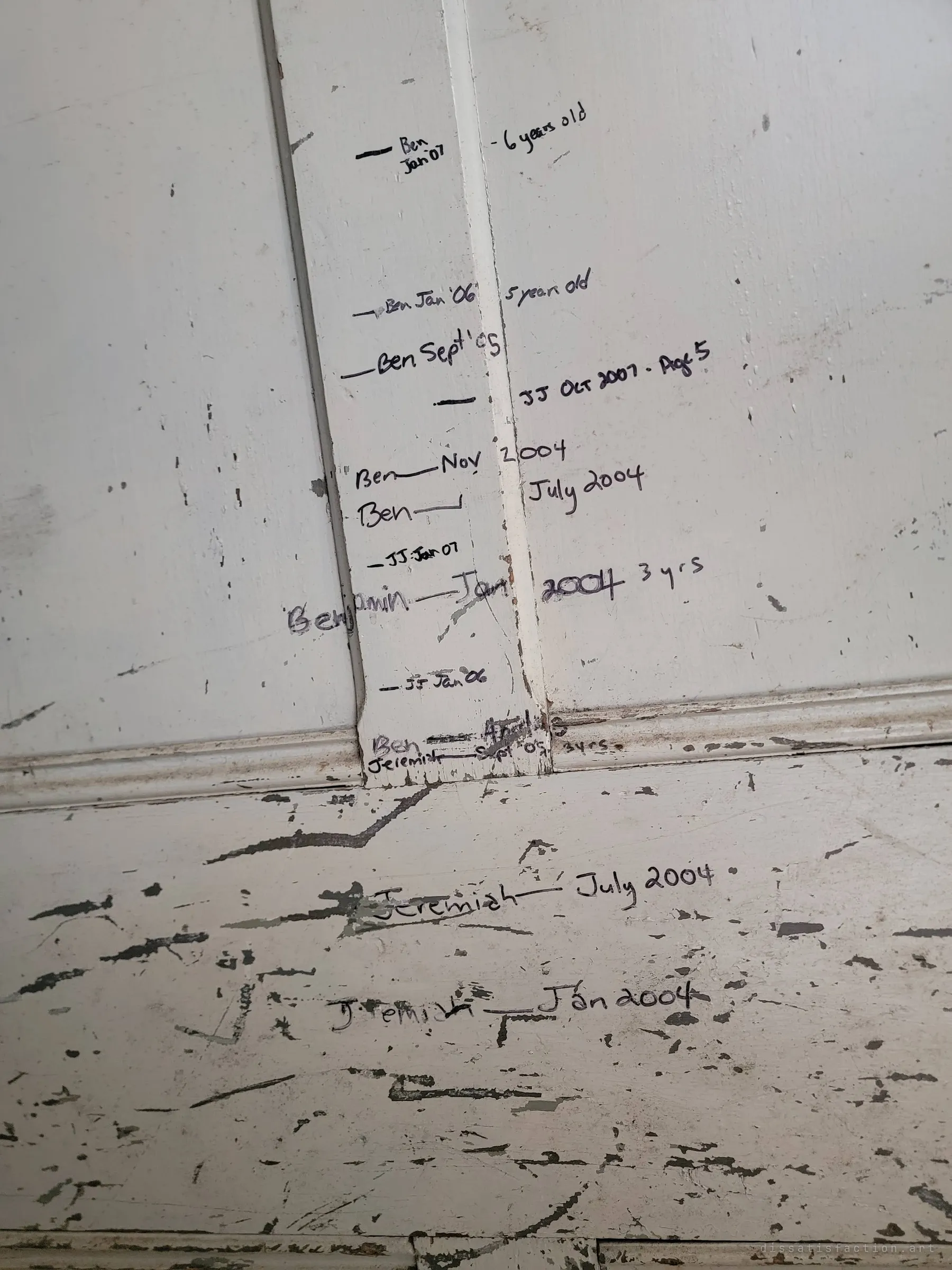 A doorframe height chart in marker, two children measured again and again between 2004 and 2007. The marks stop, like the house did.