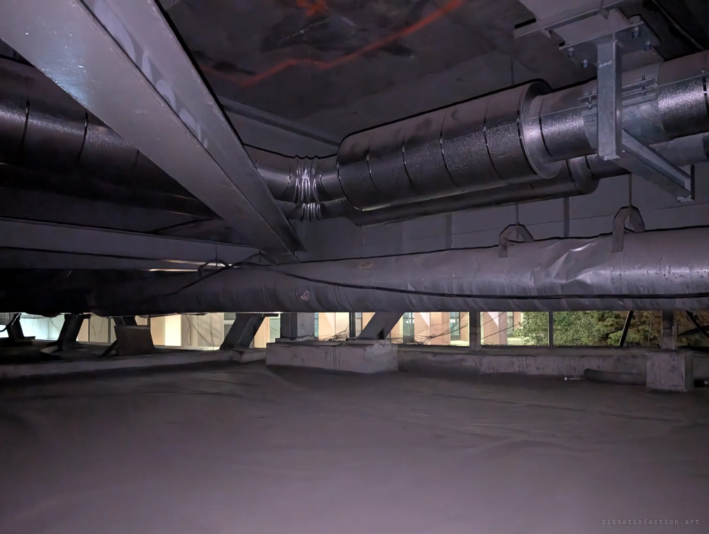 Steel beams and insulated ducts cross a wide, flat membrane-covered floor in a low void, with a thin strip of the outside world visible at the far edge. It shows how shallow and vast the hidden level is.