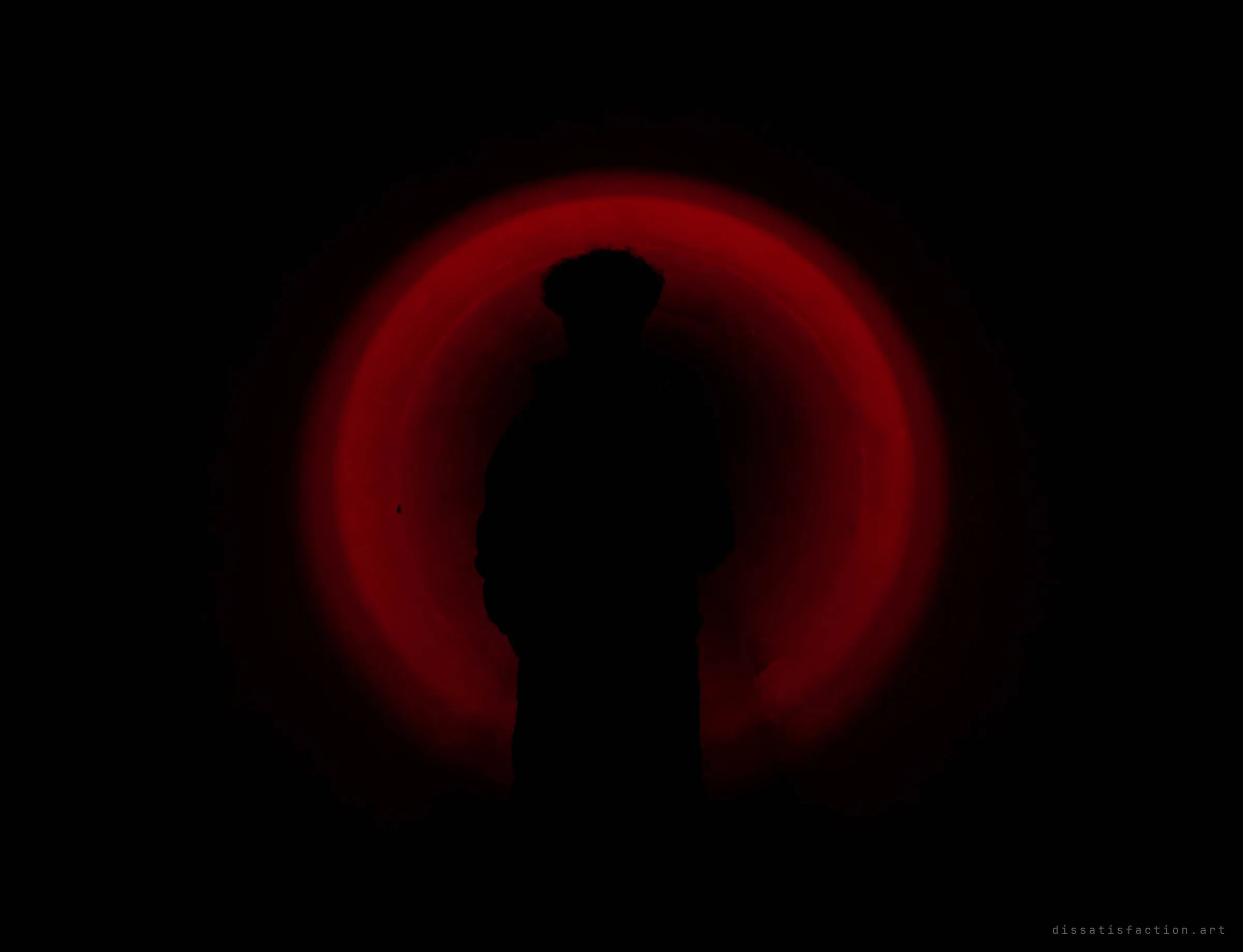 A figure in silhouette stands inside a pipe, ringed by a deep red glow of light on the curved walls. A mood shot deep in the tunnel.