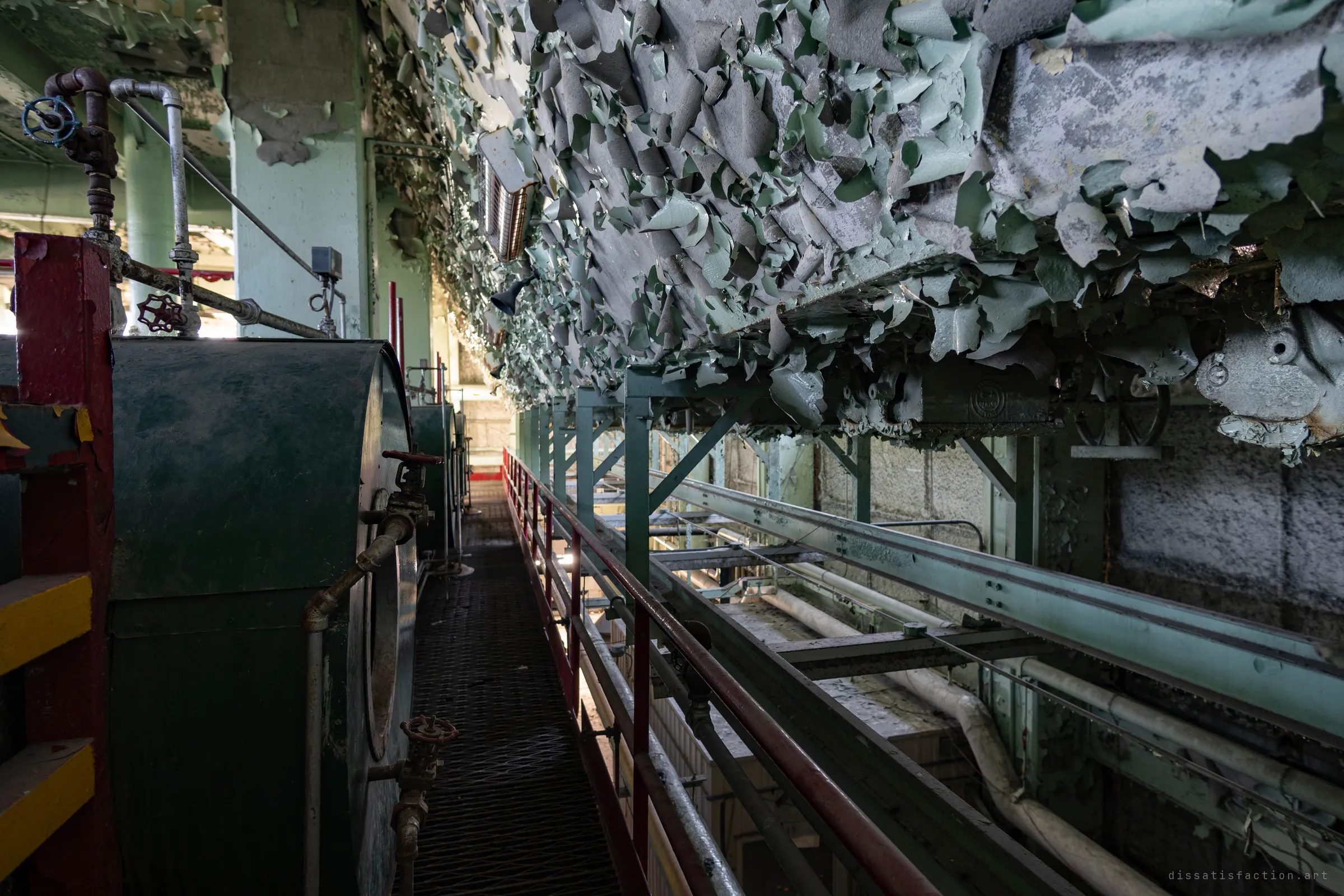 A narrow catwalk along the tops of the boilers, the ceiling above hanging with thick curls of peeling green paint.