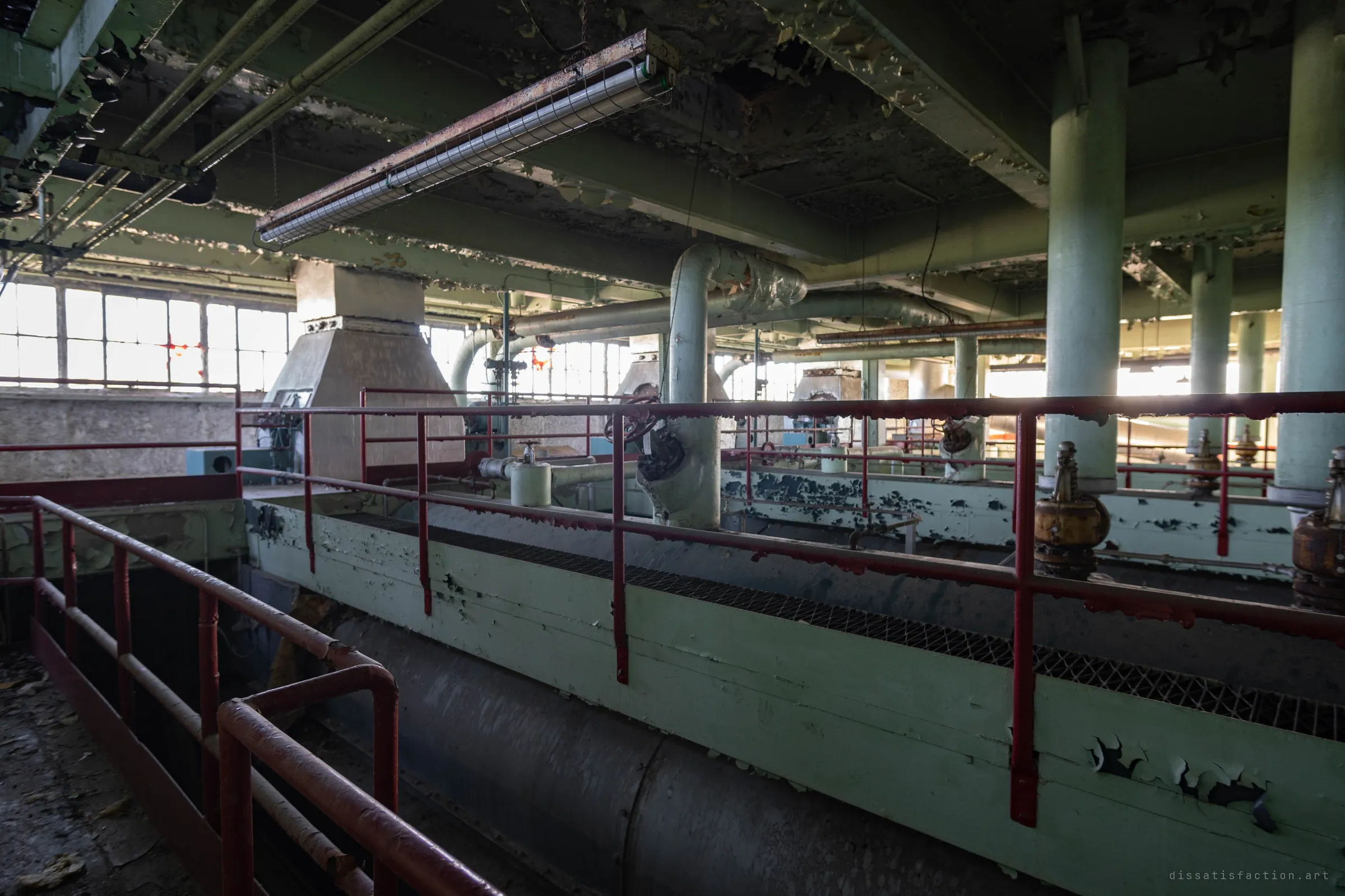 The upper deck of the boiler house: red railings over the boiler drums, round columns and a long band of steel windows glowing with daylight.