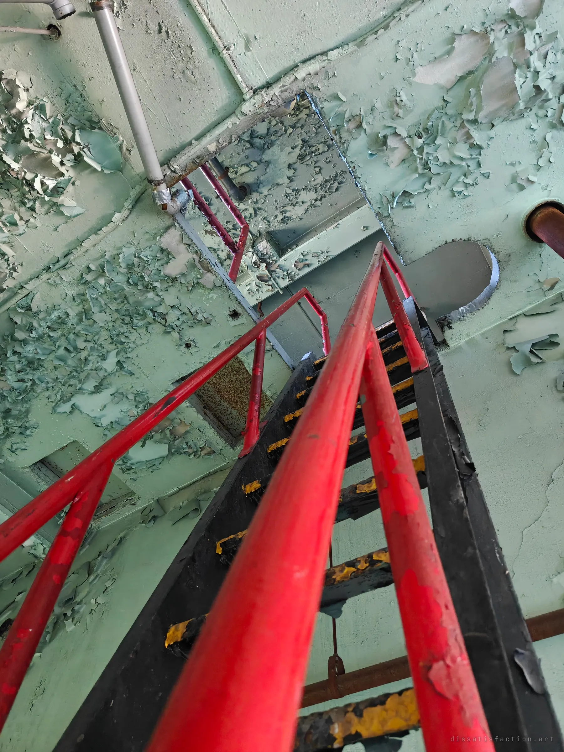 A steep black ship's ladder with bright red handrails climbs toward a hatch in a ceiling of curling mint-green paint. The low angle makes the climb feel endless.