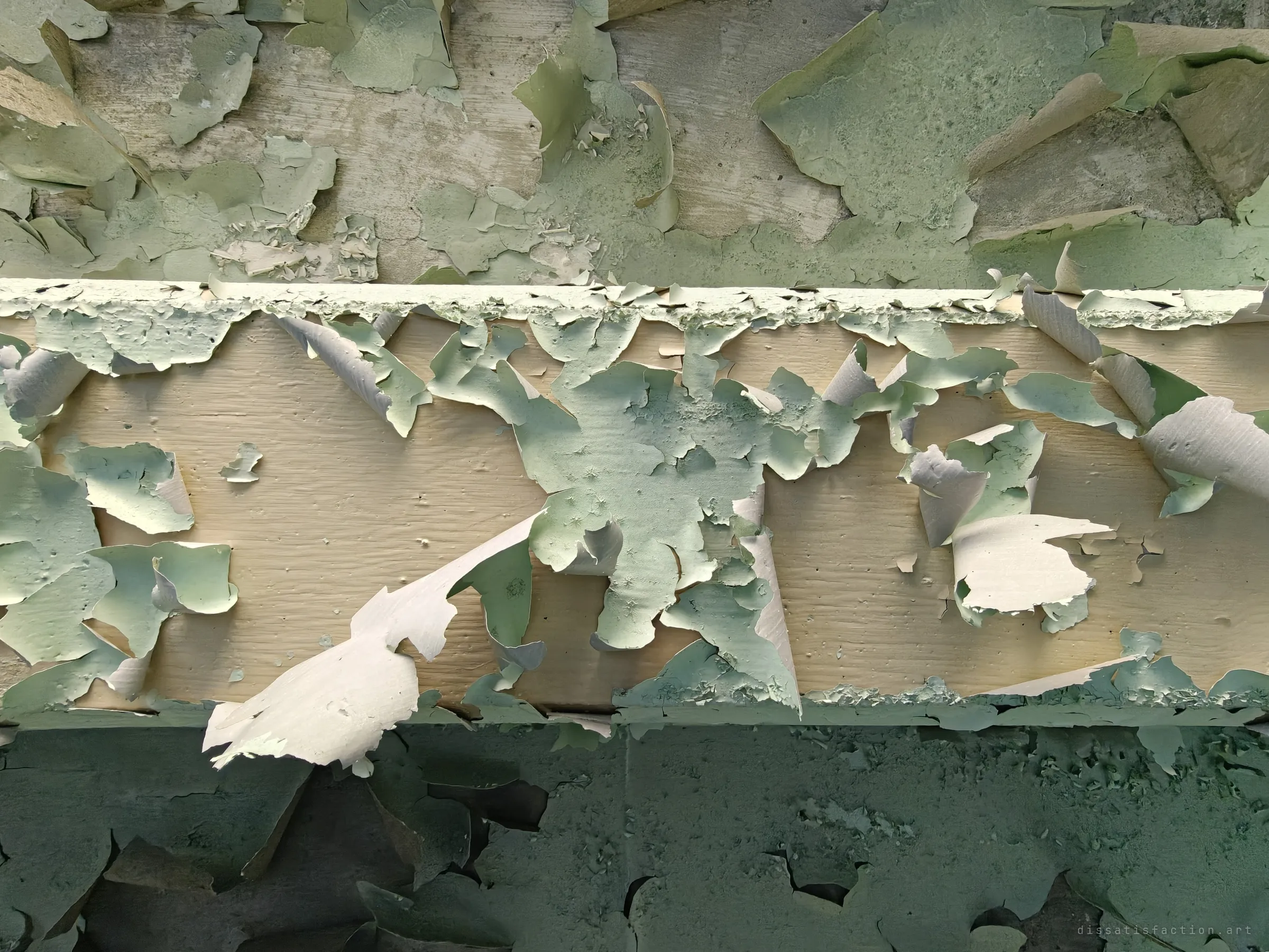Close detail of a beam where layers of green and cream paint peel away in curls. Decades of repainting come apart in one frame.