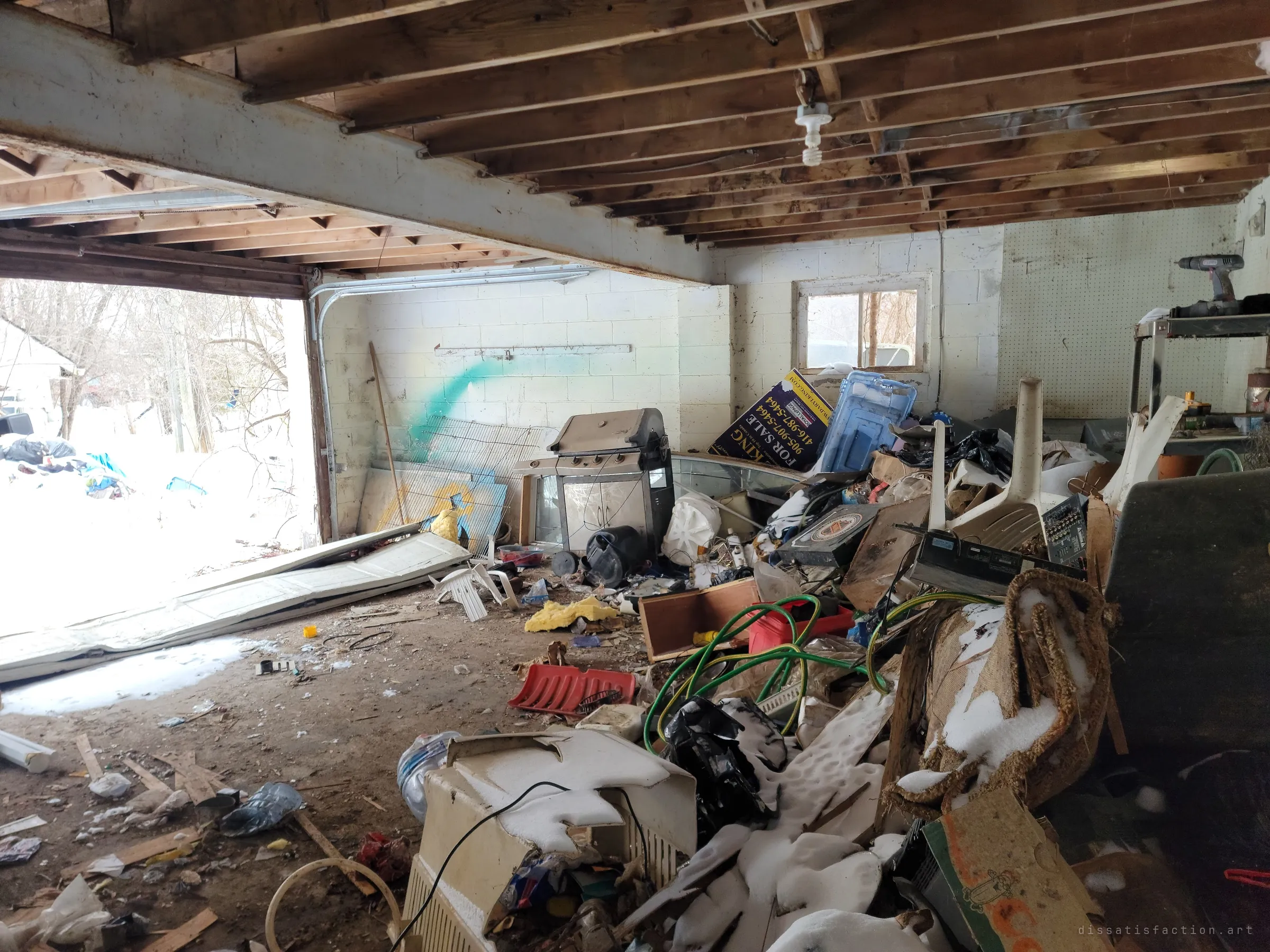 Inside the garage, the door has fallen in and joists hang bare over a heap of hoses, a barbecue and broken appliances. A discarded for-sale sign leans in the pile, a leftover from before the house was left.