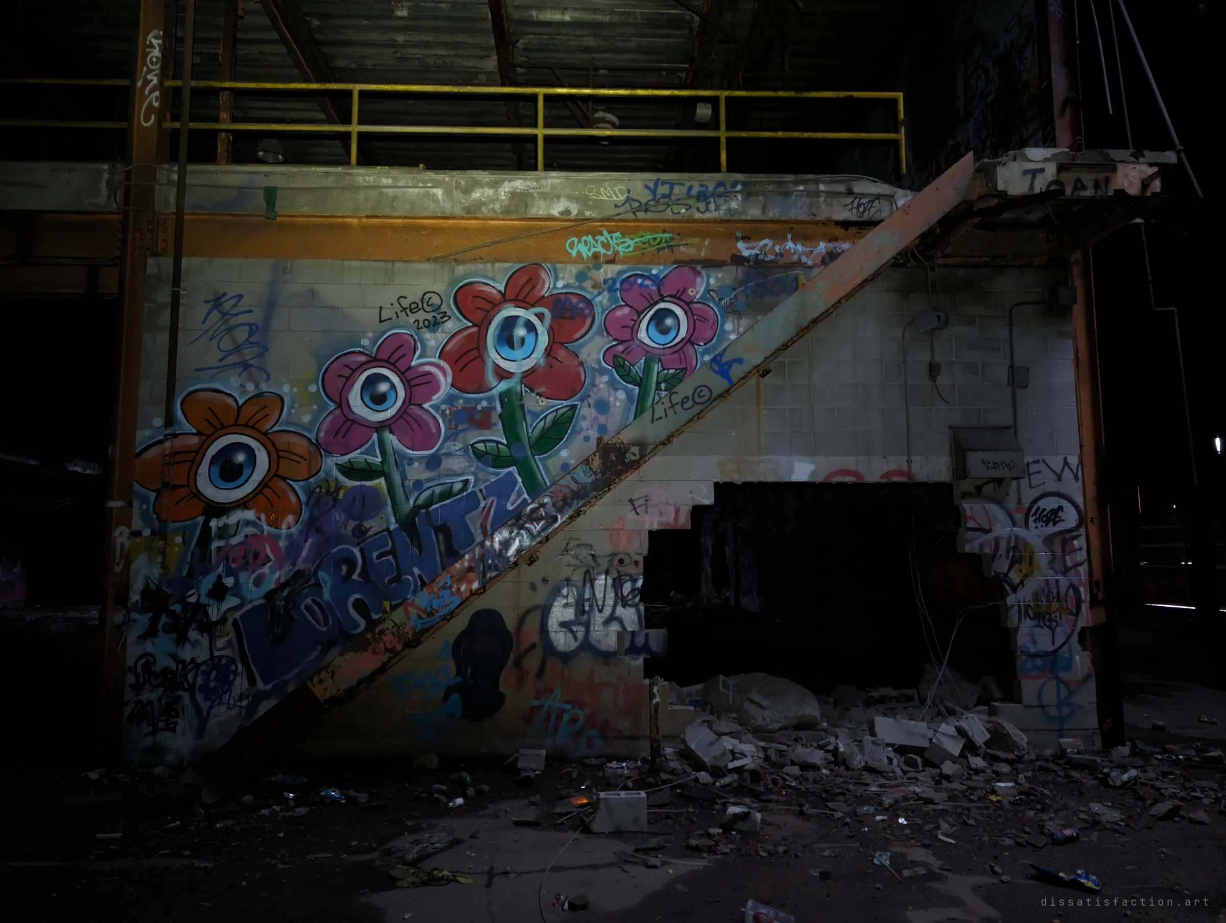 A close look at the eyeball-flower mural beside the rusted stair to the mezzanine, with a hole knocked through the block wall below. Here the graffiti is the main subject.