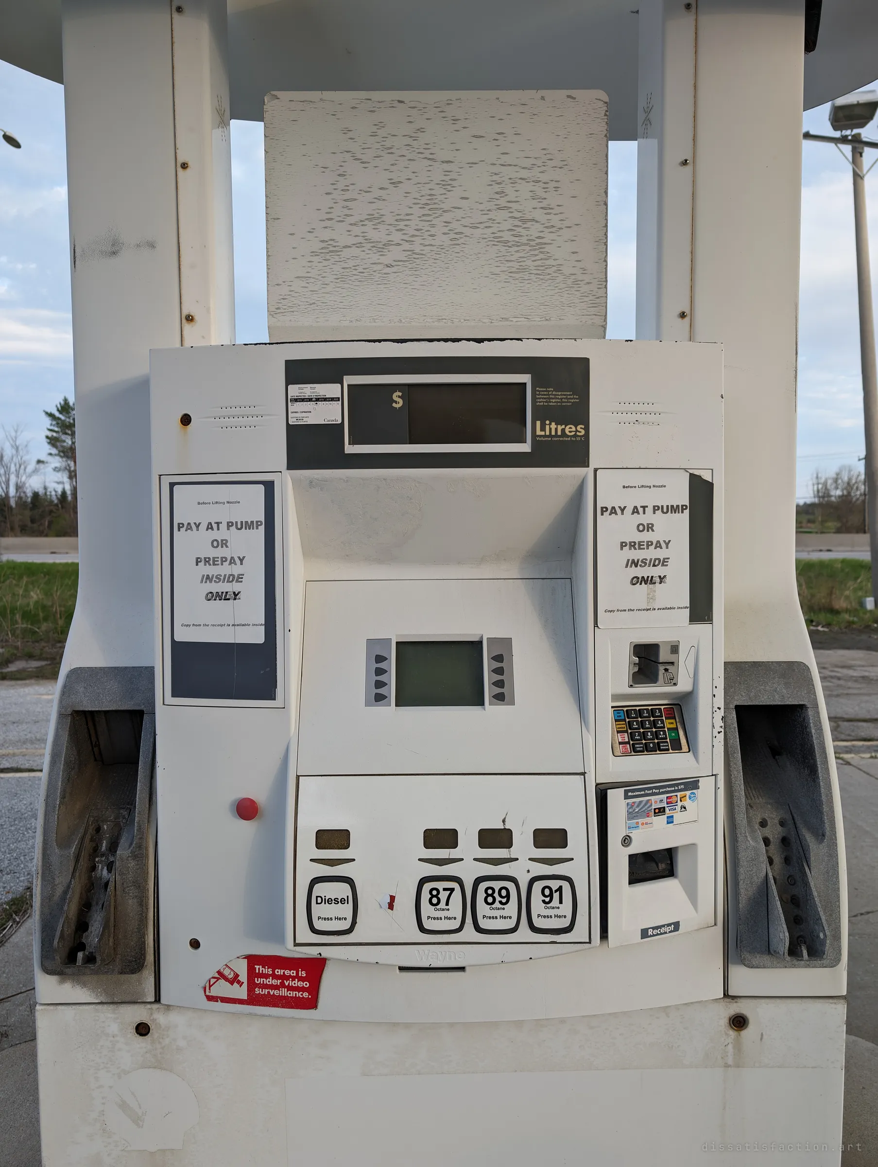 A disused fuel pump, its displays blank and its price-board faded to bare white, still asking customers to pay at the pump or inside.