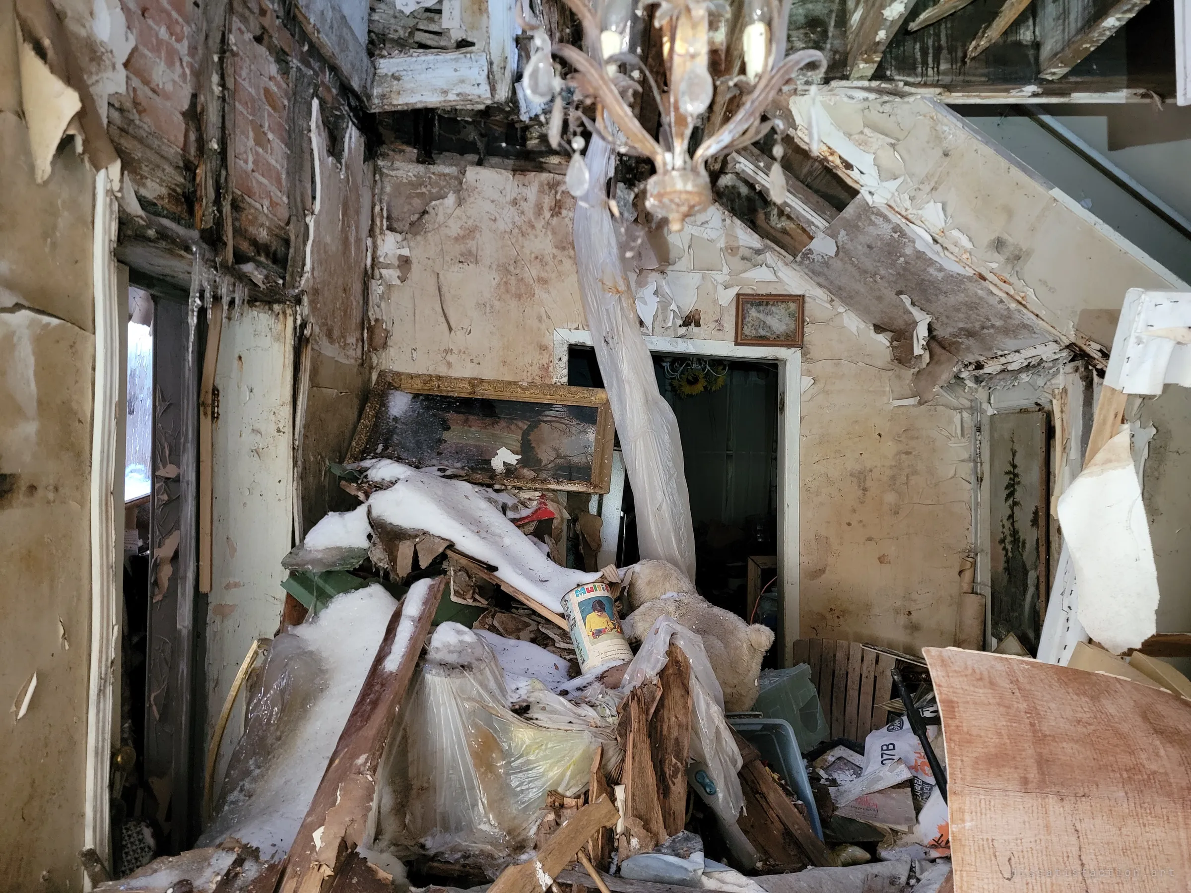 Inside, the ceiling has fallen in, burying the front hall in snow, boards, a gilt-framed painting and a teddy bear under a dangling crystal chandelier. Peeling plaster and a broken staircase show how far the collapse has gone.