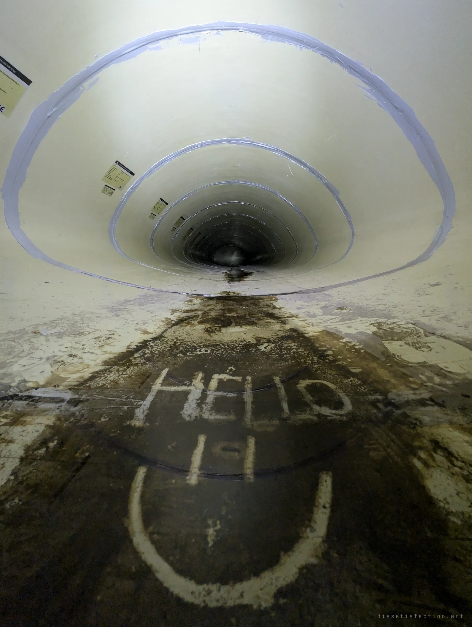 Inside the smooth fibreglass liner, sealed joints ring away into the dark, while a smiley face and a greeting are traced in the silt on the floor.
