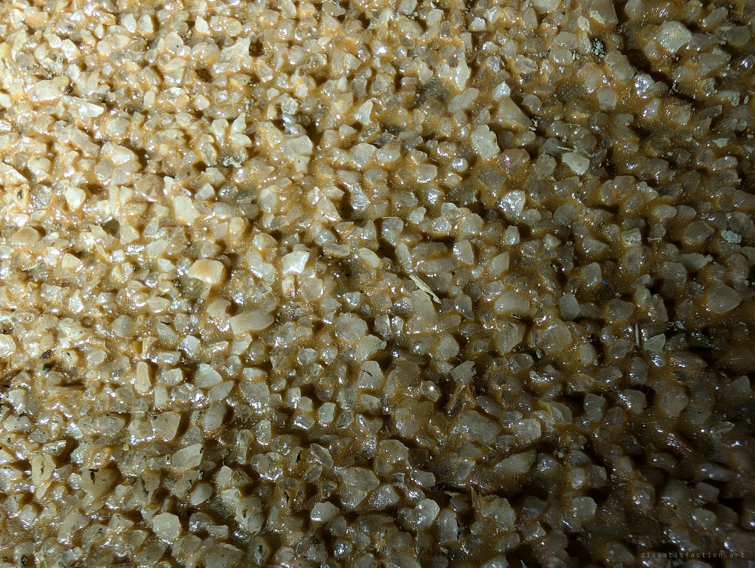Close-up of the new liner's wet, glassy aggregate surface, grains of quartz set in an amber resin.