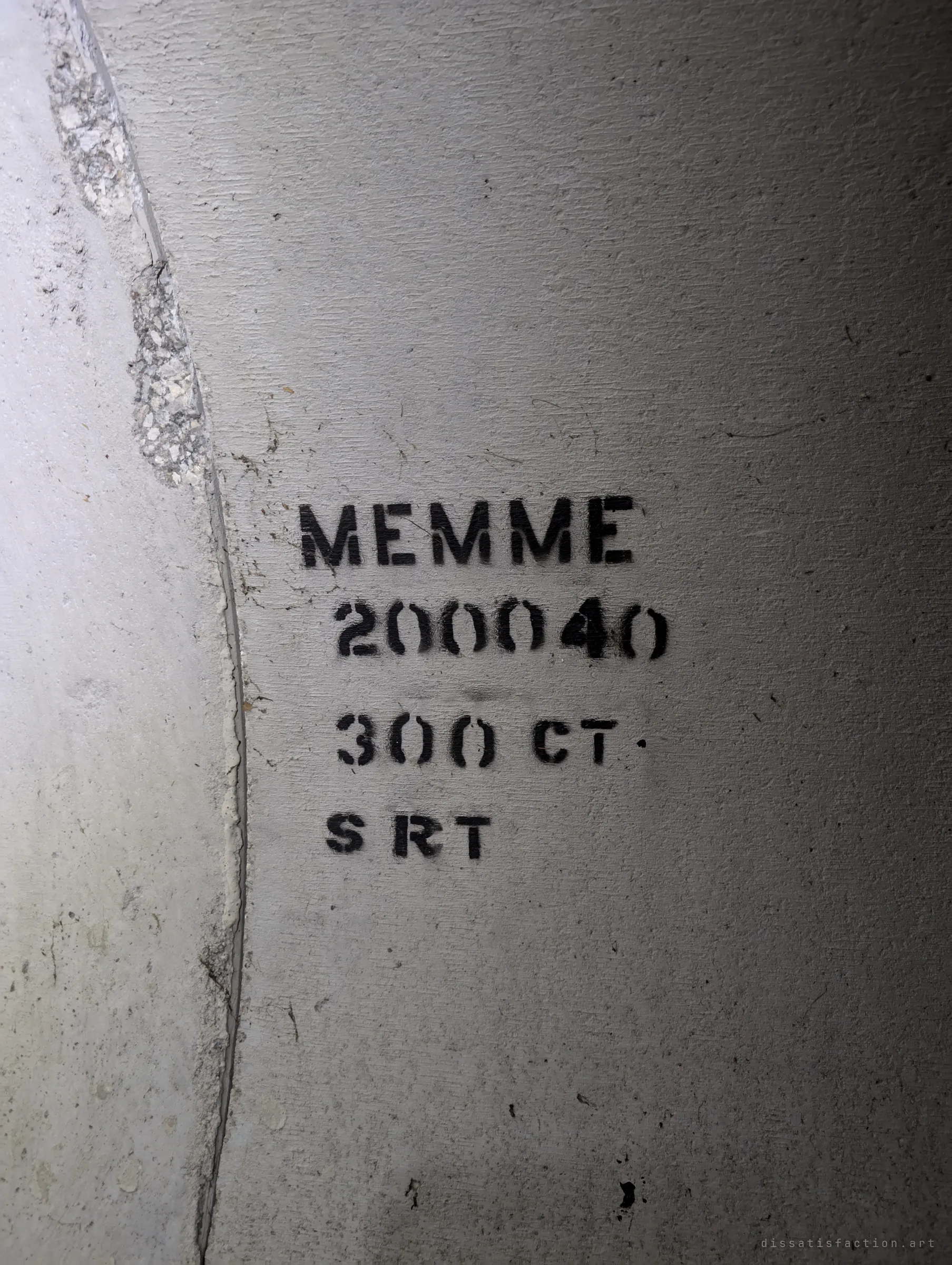 A stencilled marking in black on the concrete pipe wall beside a crumbling joint, the kind of code crews leave on each section.
