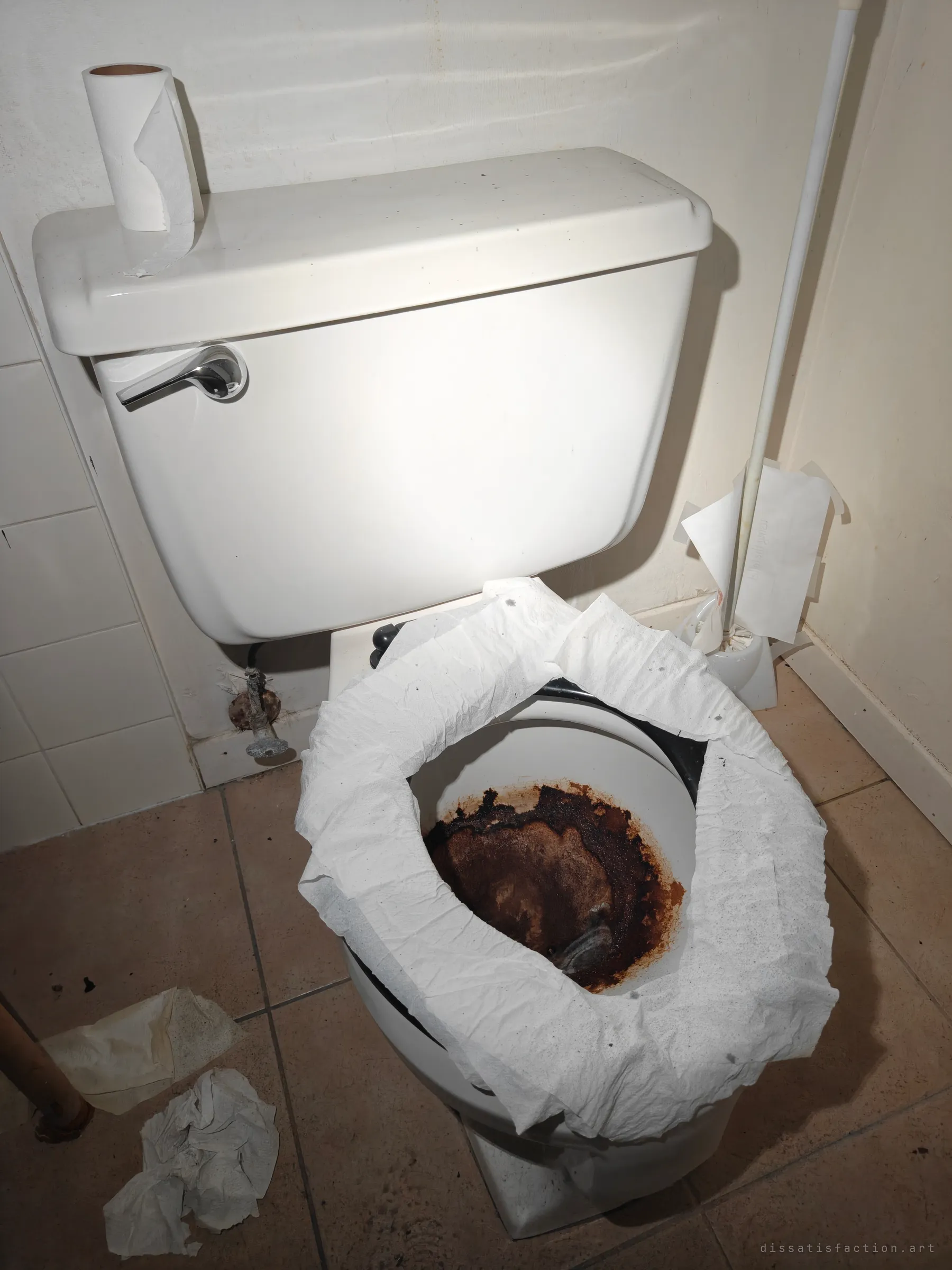 A toilet with a rust-black, dried-out bowl, its seat covered in paper towels and more crumpled paper on the floor. A grim close-up of what neglect does to a room.