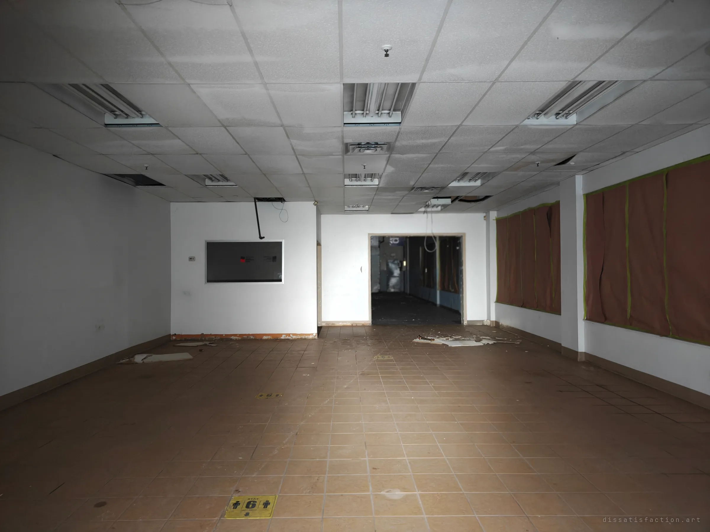 An empty tiled retail unit with a grid ceiling, papered-over windows and a blank display board, a doorway opening onto a darker corridor. A faded floor sticker still asks people to keep their distance.
