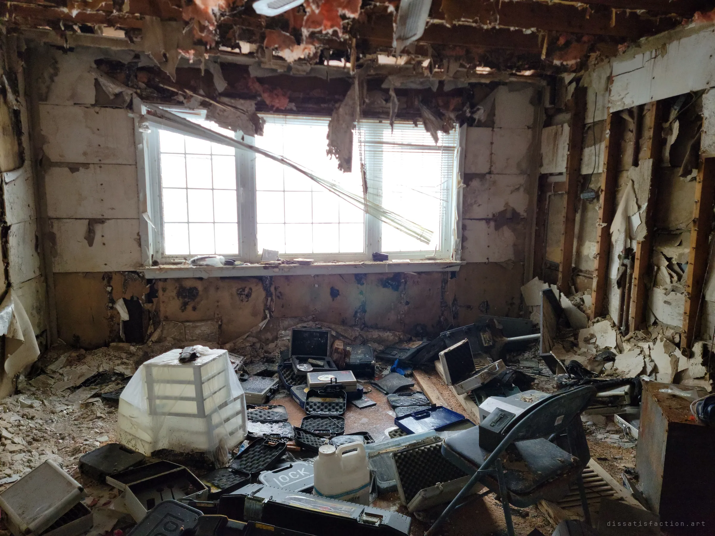 A gutted room whose floor is covered in dozens of open, empty hard gun cases beneath a bright window. The scatter of cases hints at why the owner earned the prepper name.