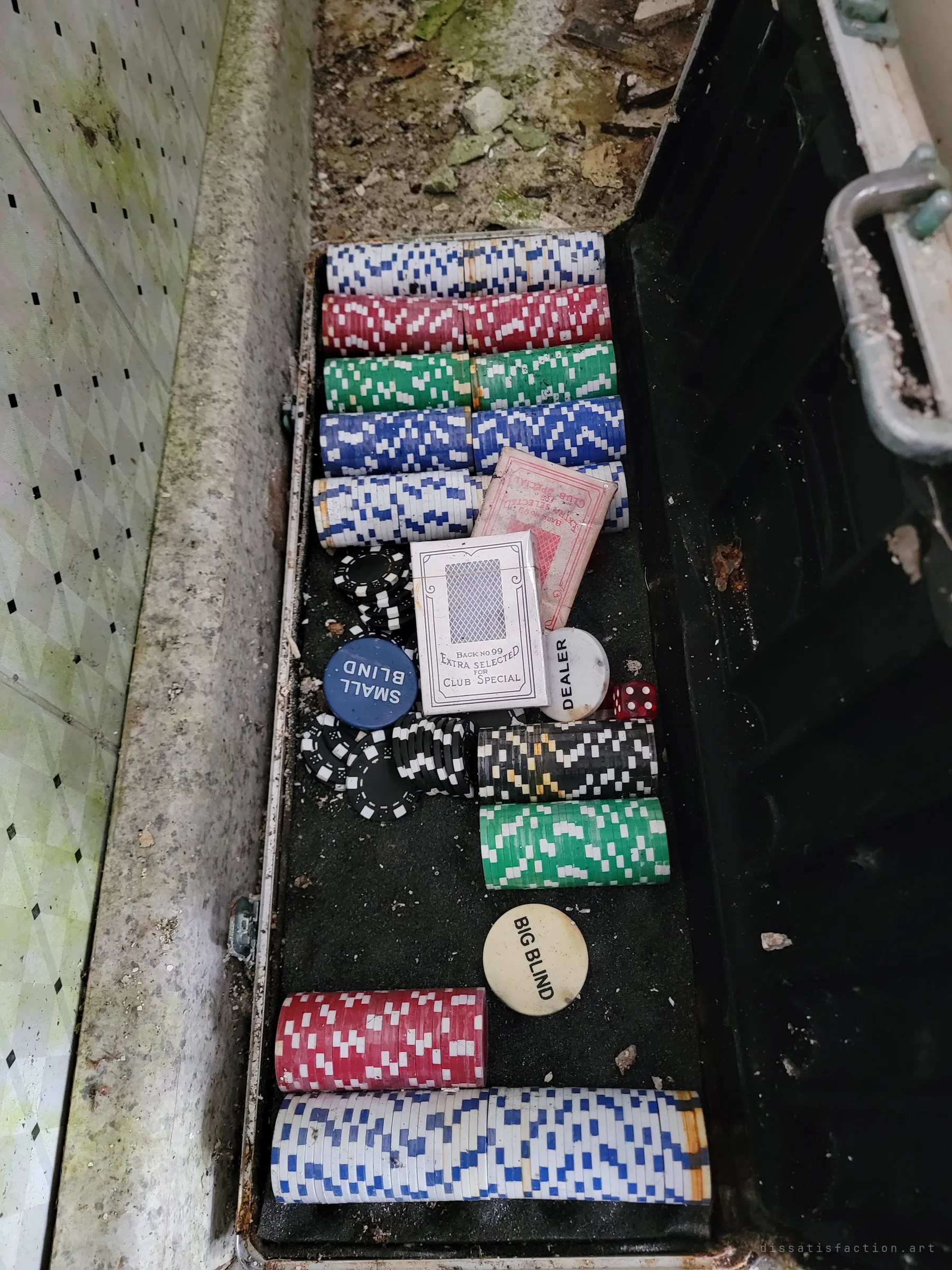An aluminium poker case still holds its stacked chips, blind buttons, dealer puck and card decks, a small leftover of game nights in the abandoned home.